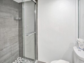 Um banheiro moderno com box de vidro, vaso sanitário e pia branca.
