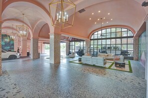 Eine geräumige Lobby mit hoher Decke, großen Fenstern und einer Sitzecke mit Sofas und einem Couchtisch.