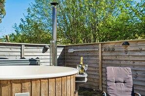 Ein Whirlpool mit Holzterrasse, Liegestuhl und einer Flasche Champagner.