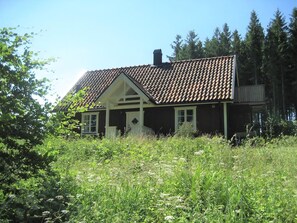Ein Haus mit Ziegeldach, umgeben von üppigem Grün und hohen Bäumen.