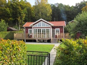 A two-story house with a red roof, large windows, and a wooden deck. - Panoramic sea-view from the house (Bräkne-Hoby)