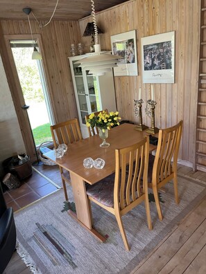 Ein Holztisch mit Stühlen, eine Vase mit gelben Blumen und zwei Kristallgläsern darauf.