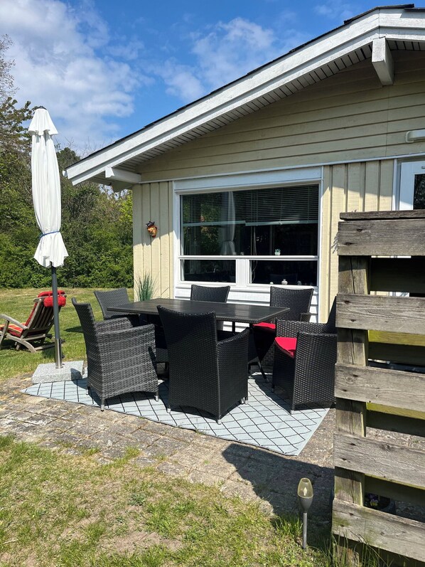 Eine Terrasse mit Tisch und Stühlen, einem Sonnenschirm und einem Holzzaun.