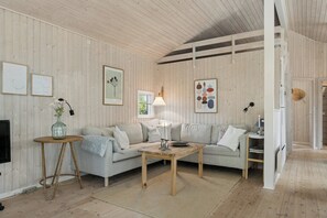 Ein Wohnzimmer mit Sofa, Couchtisch, Lampe und gerahmten Kunstwerken an den Wänden.