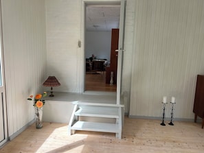 A room with a white bench, a vase with flowers, and two candle stands. - Holiday home in peaceful natural surroundings (Nørre Snede)