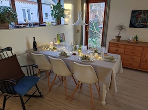 A dining area with a table set for four, chairs, a candle, and a bottle of wine. - Sea view and calm near the shore in Thorøhuse (Assens)