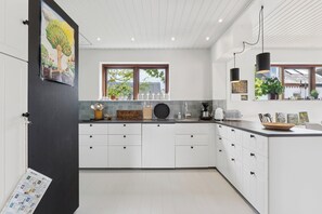 A modern kitchen with white cabinetry, a black countertop, and a window with a view of the outdoors. - Sea view and calm near the shore in Thorøhuse (Assens)