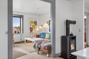 Ett mysigt vardagsrum med en öppen spis, en soffa, ett soffbord och en tavla på väggen.