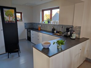 Ett modernt kök med en central köksö, en inbyggd ugn och ett fönster med utsikt över omgivningen.