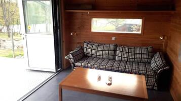 En stuga med träpanel på insidan, inredd med en soffa, ett bord och ett fönster.