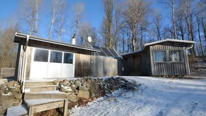 Une cabane en bois avec un garage, un mur en pierre et un sol recouvert de neige.