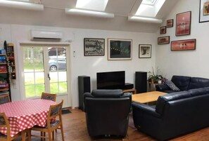 Ein Wohnzimmer mit kariertem Tisch, schwarzer Ledersofa und einem Flachbildfernseher.