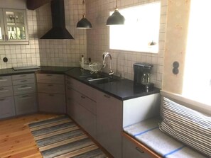 Eine Küche mit schwarzem Arbeitsplatz, weiß gefliestem Fliesenspiegel, einem Fenster und Holzboden.