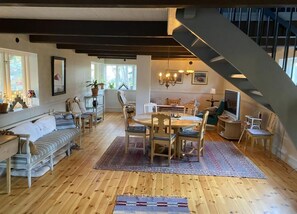 Ein geräumiger Wohnbereich mit Esstisch, Stühlen, einer Couch und einer Treppe.
