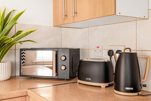 A kitchen with a microwave, toaster, and kettle on a countertop. - NEW! 3BR House, free on-street parking, near Nottingham City Centre (Nottingham)