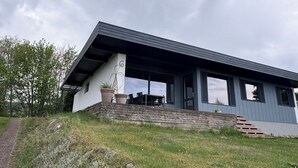 A modern house with a sloped roof, a covered patio, and a stone staircase leading to the entrance. - Marvelous views & hygge in a cosy summer cottage (Asnæs)