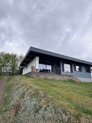 A modern house with a sloped roof, a covered patio, and a stone staircase leading to the entrance. - Marvelous views hygge in a cosy summer cottage (Asnæs)