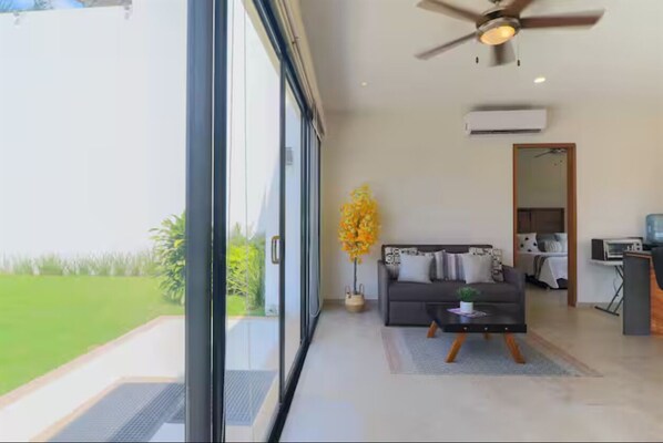 Een moderne woonkamer met een bank, salontafel en een groot raam met uitzicht op een groen landschap.