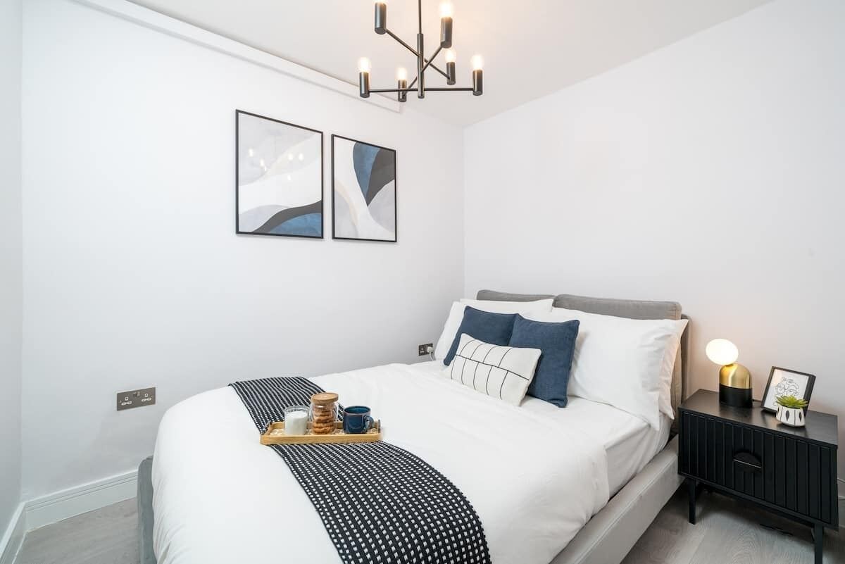 A modern bedroom with a bed, bedside table, and artwork on the wall.