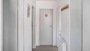 A hallway with white walls, a wooden floor, a door with a circular decoration, and a sign on the wall. - Gorgeous home in Barth with house a panoramic view (Barth)