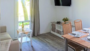 A room with a sofa, a dining table with chairs, a TV mounted on the wall, and a window with curtains. - Gorgeous home in Barth with house a panoramic view (Barth)