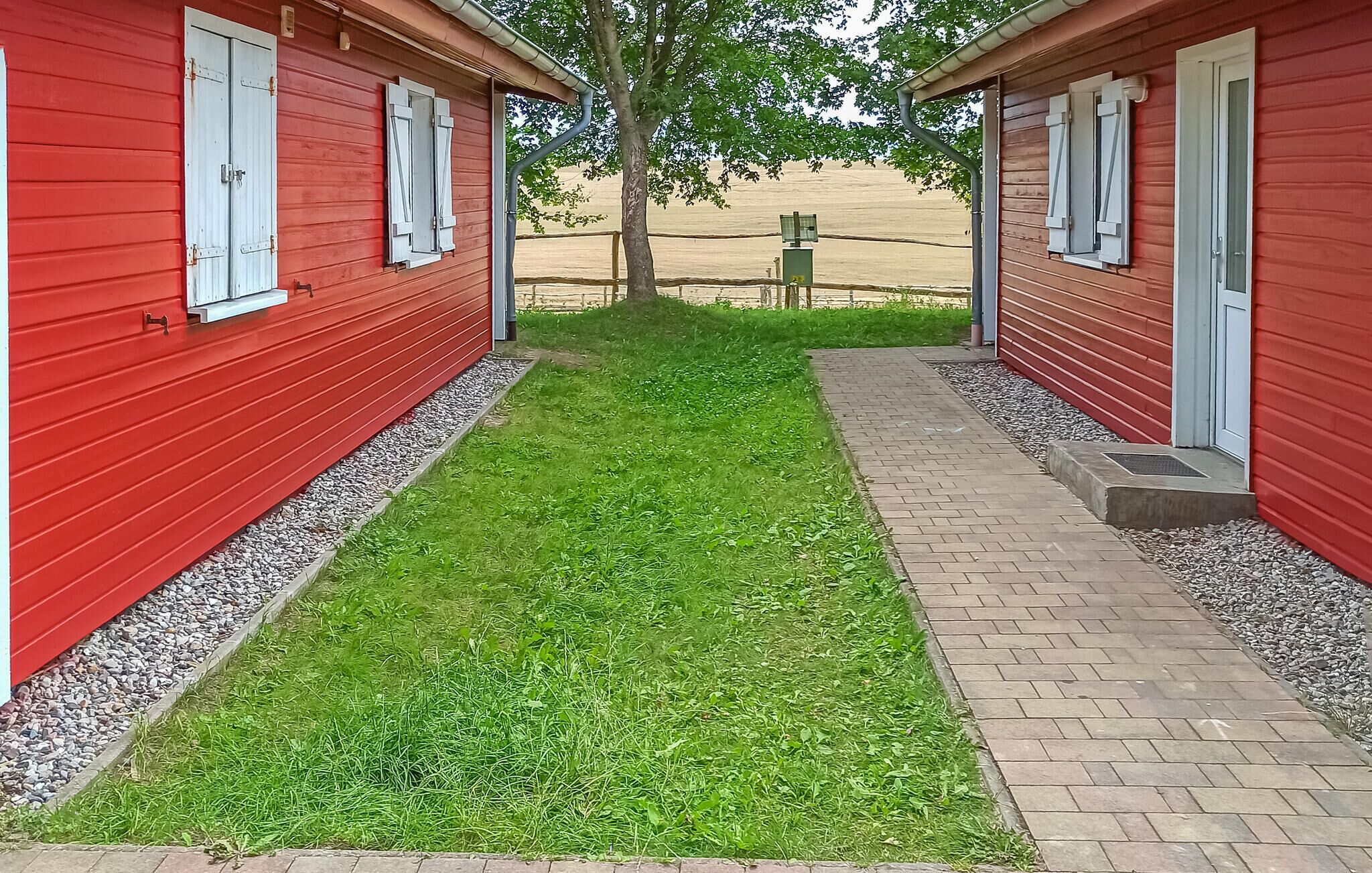 Un bâtiment rouge avec un chemin pavé et une zone herbeuse.