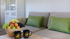 A living room with a sofa, green cushions, a wooden table with fruit and two mugs, and a white cabinet with glass doors. - Gorgeous home in Barth with house a panoramic view (Barth)