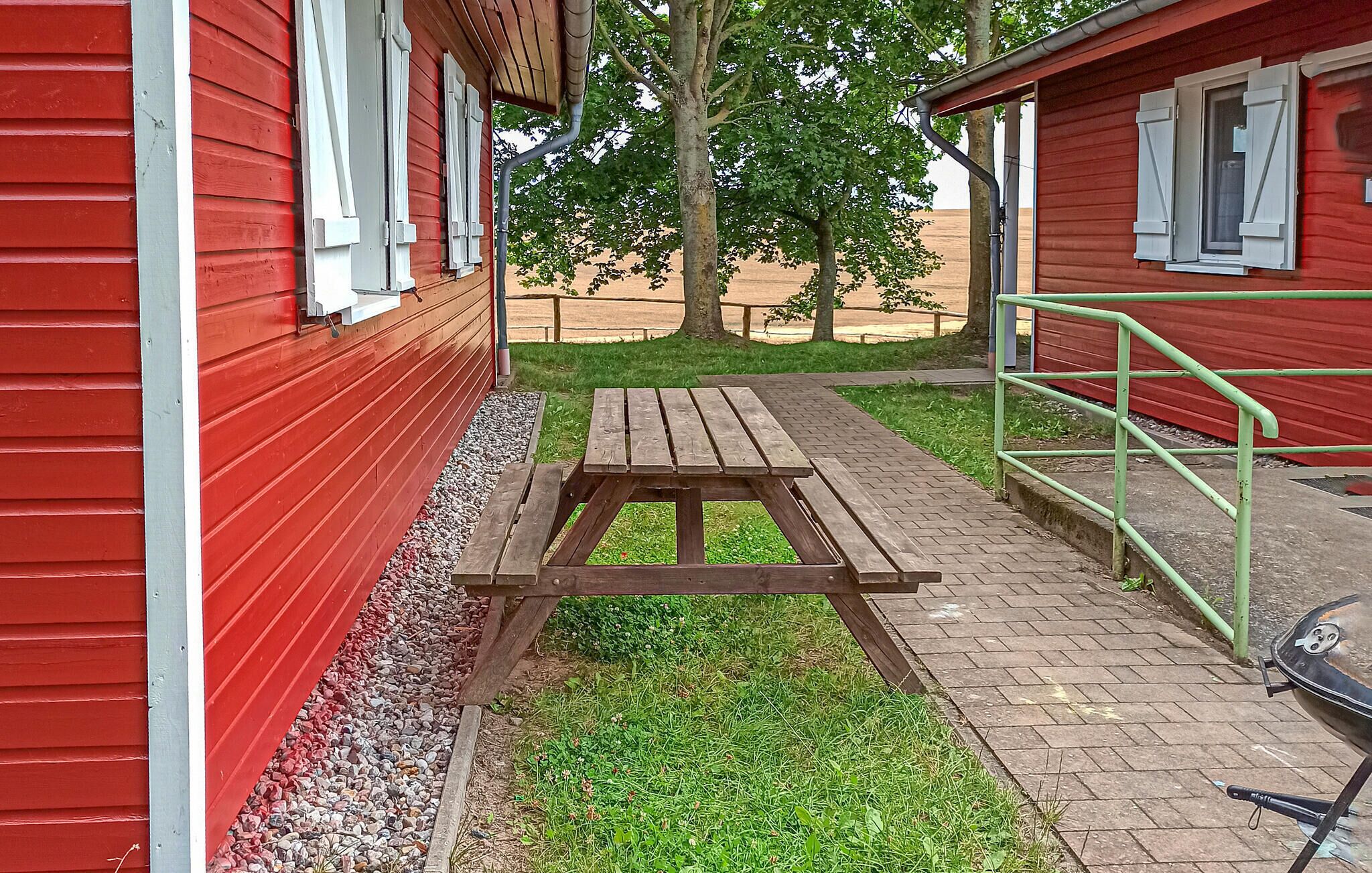 Een rood gebouw met een picknicktafel ervoor, een gazon en een metalen hekwerk.