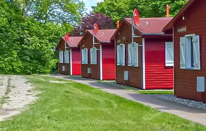 A row of red wooden cabins with white shutters, a gravel path, and green foliage in the background. - 2 bedroom stunning home in Barth (Barth)