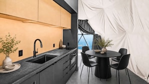 Una cucina moderna con un piano di lavoro nero, un lavello e un'area pranzo con un tavolo rotondo e sedie.