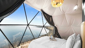 Una camera da letto con un letto, un comodino, una lampada e vista mare.