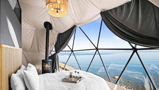 Una camera da letto con un letto, un camino, un vassoio con oggetti e vista sul paesaggio.