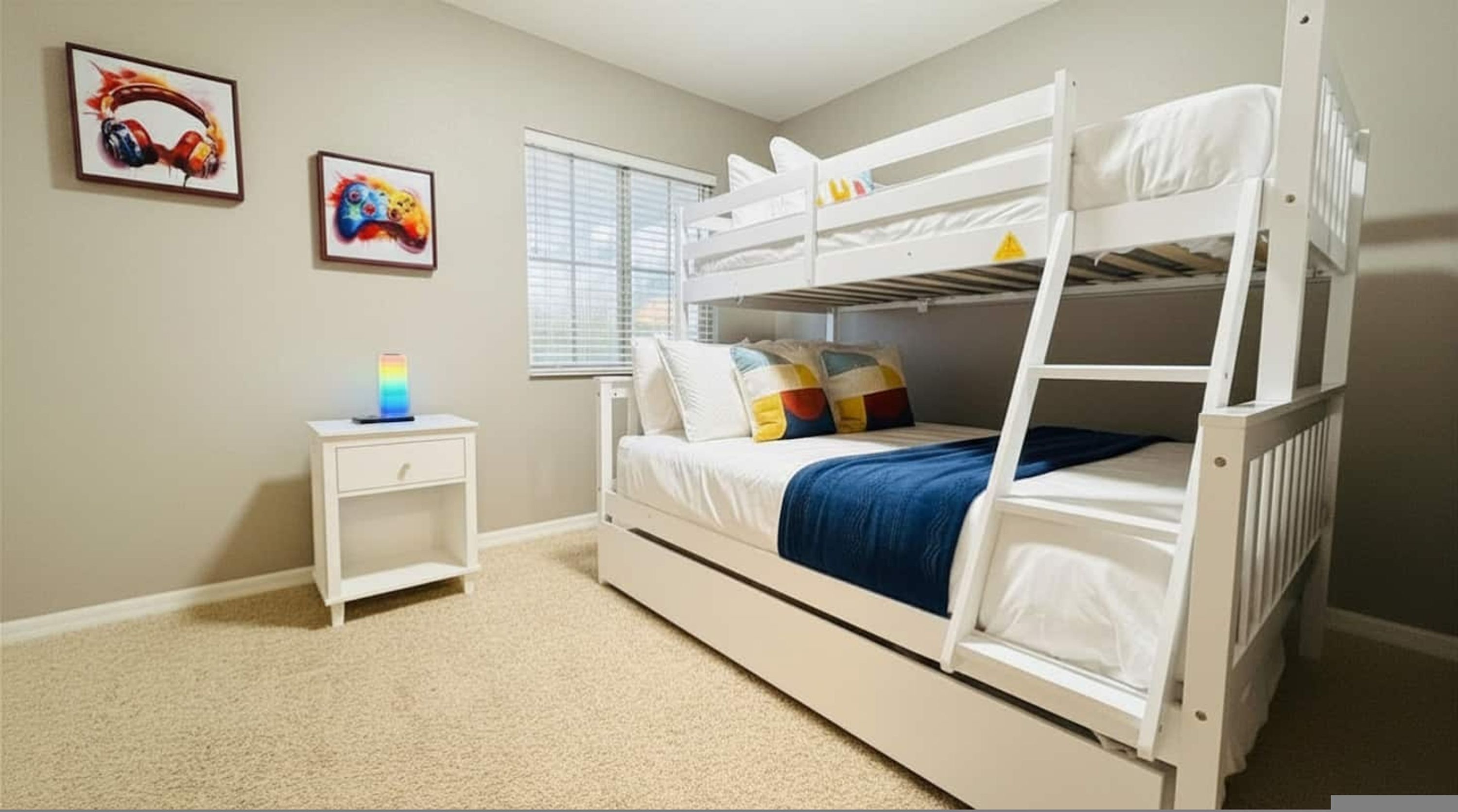 A bunk bed room with a nightstand, a lamp, and two wall art pieces.