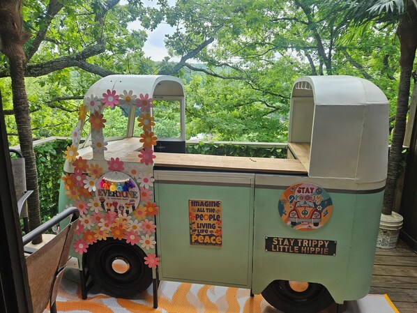 Een stilstaand voertuig met een bord waarop staat 'Iedereen is hier welkom' en 'Stay Trip Happy Little Hippie'.
