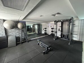 Ein Fitnessraum mit Trainingsgeräten, einem Spiegel und einer Ziegelwand.