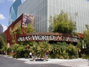 Das äußere Erscheinungsbild des Dallas World Aquarium mit einer großen Schautafel, moderner Architektur und umgebender Bepflanzung.
