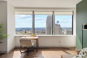 Ein modernes Zimmer mit großem Fenster, Schreibtisch, Stuhl und Lampe.