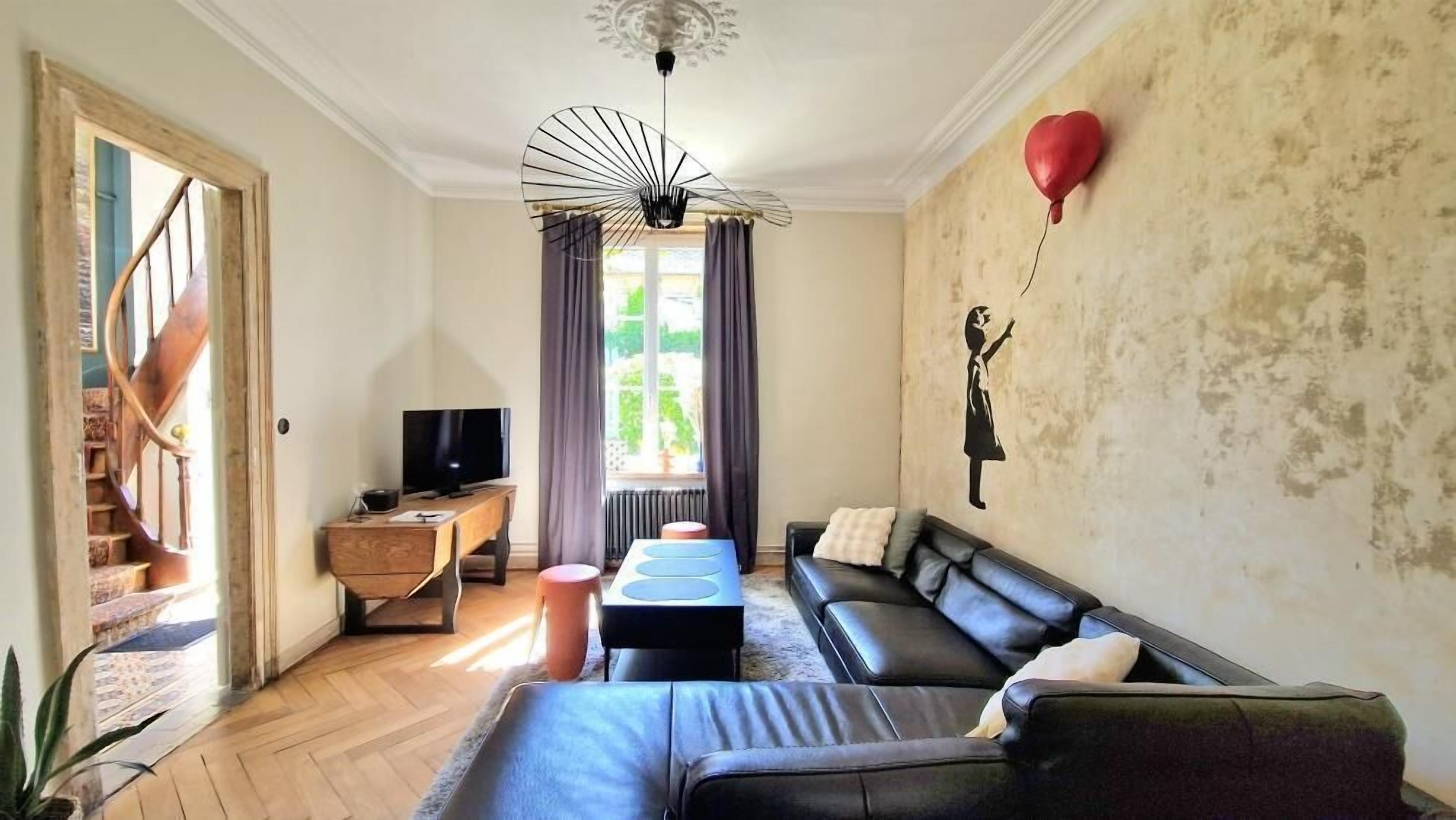 Un salon avec un canapé, une table basse, un téléviseur et un escalier.