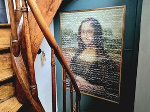 A framed portrait with bubble wrap, a wooden staircase, and a light fixture. - Gîtes de France® - Le Secret Des Cordelières (NEUFCHATEL EN BRAY)