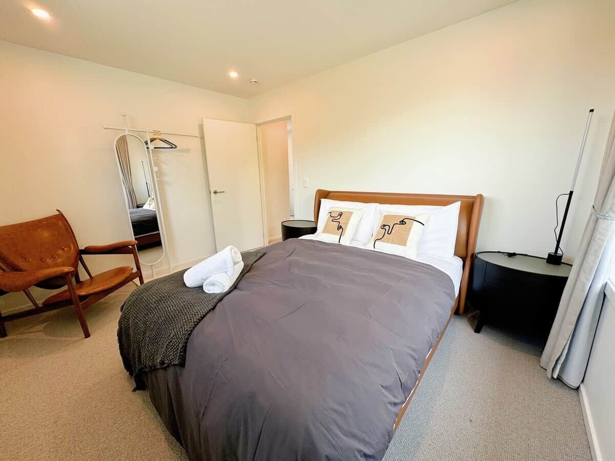 Ein Hotelzimmer mit Bett, Stuhl, Nachttisch und Spiegel.