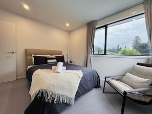Ein modernes Hotelzimmer mit einem großen Bett, einer Sitzecke und Blick ins Freie.