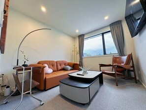 Ein modernes Wohnzimmer mit einer Couch, einem Couchtisch, einem Sessel und einem Fernseher.
