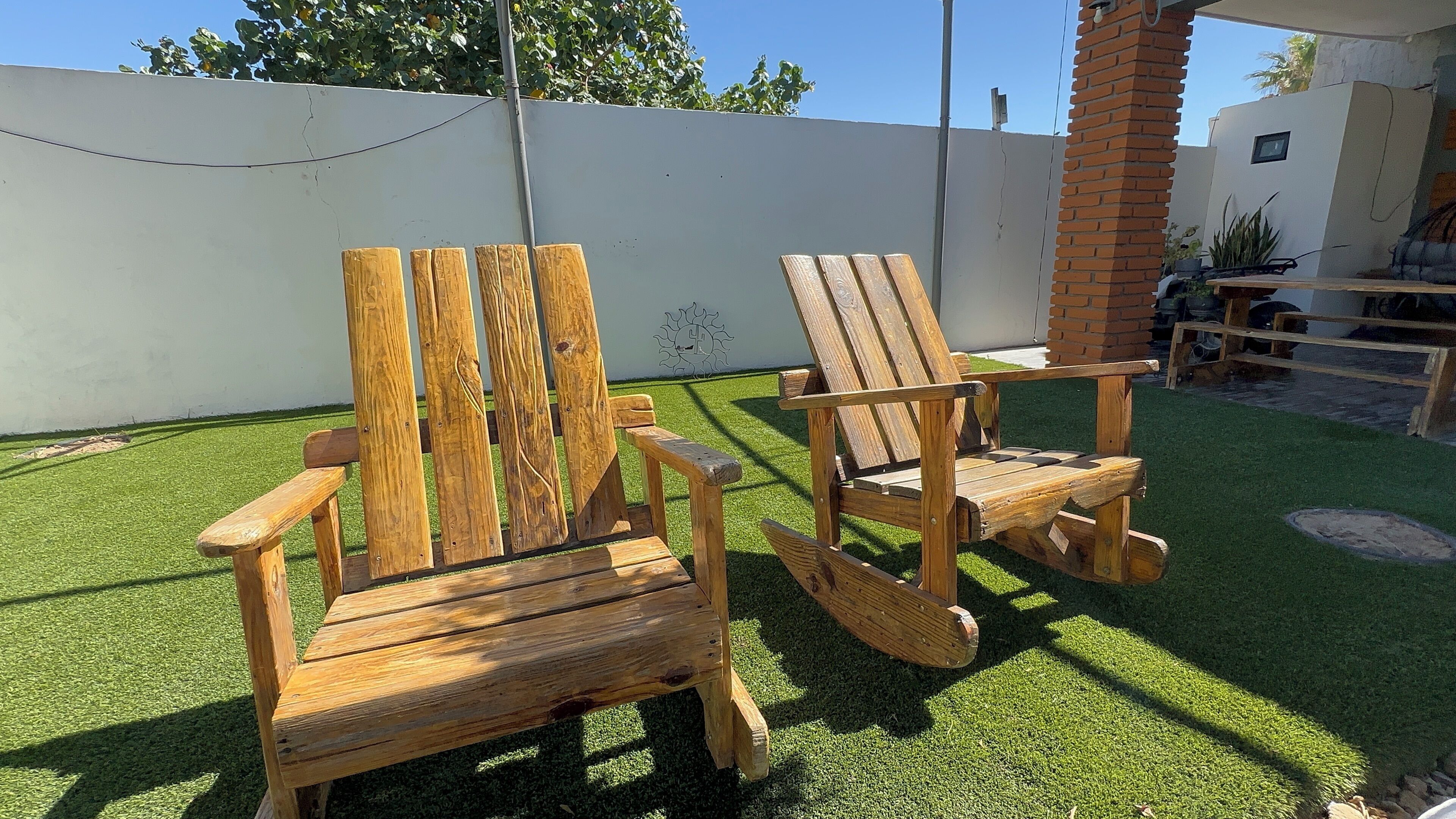 Twee houten Adirondack stoelen op kunstgras.