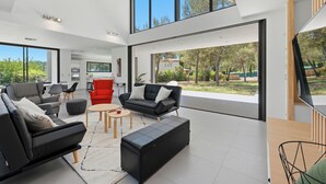 A modern living room with a large window, a dining area, and a kitchen. - Villa Stark - Pool - Gym - Pintball/Arcade/Babyfoot (Saint-Gély-du-Fesc)