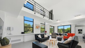 A spacious living area with a high ceiling, large windows, a mezzanine level, and modern furniture. - Villa Stark - Pool - Gym - Pintball/Arcade/Babyfoot (Saint-Gély-du-Fesc)