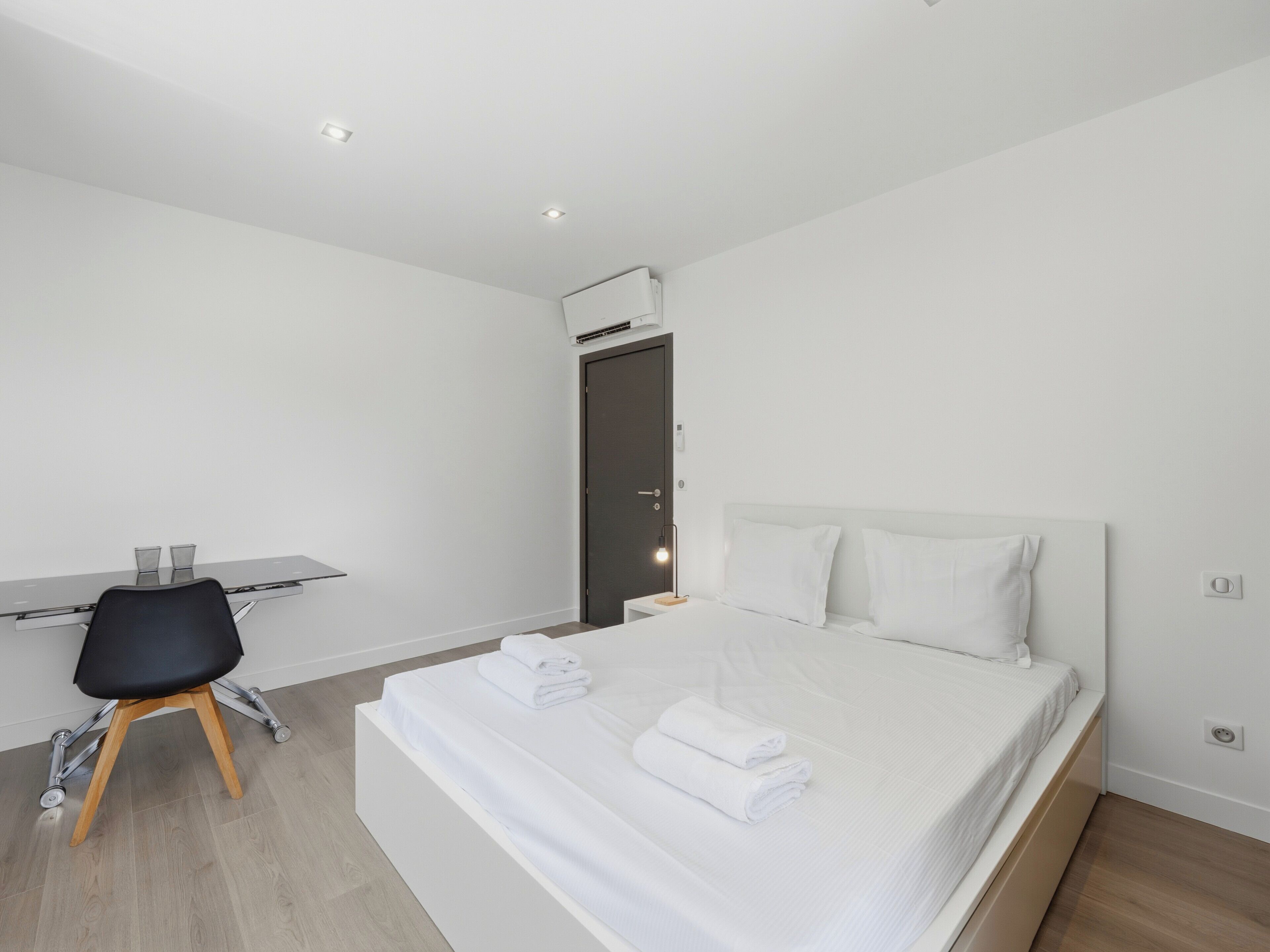 A modern hotel room with a bed, a desk, and a chair.