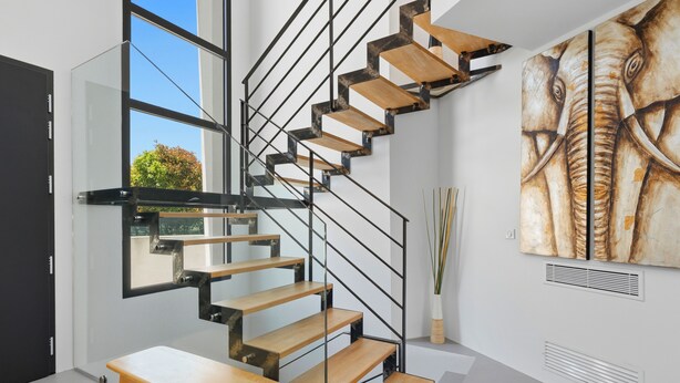 A modern interior with a spiral staircase, a dining area, and a large abstract painting. - Villa Stark - Pool - Gym - Pintball/Arcade/Babyfoot (Saint-Gély-du-Fesc)