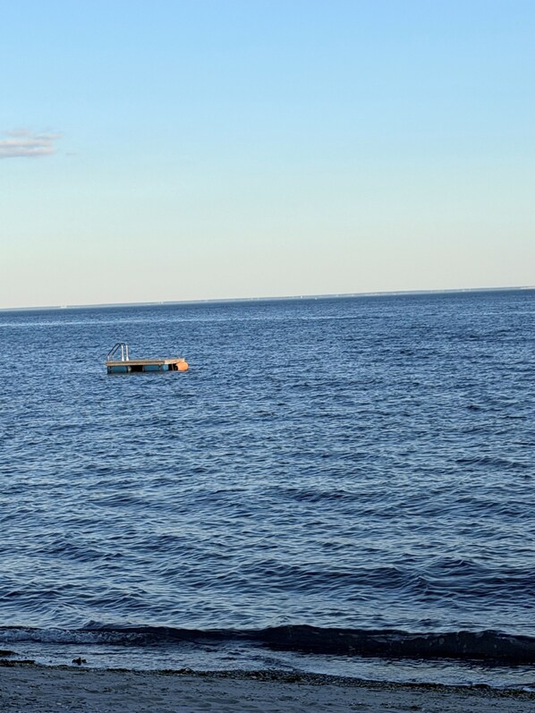 A calm sea with a small dock extending into the water.