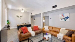 Ein modernes Wohnzimmer mit zwei Sofas, einem Glastisch und einem Essbereich mit Tisch und Stühlen.