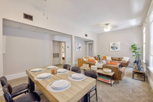 Una sala moderna con comedor, un conjunto de sofás y una televisión.